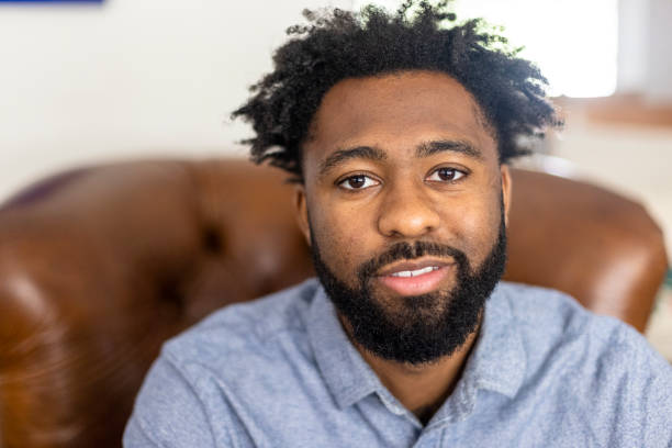 A portrait of a young black man at home smiling.